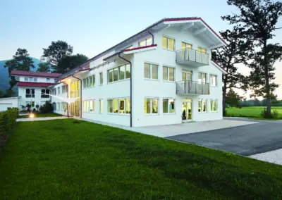 Modern, white OilDoc office building in green countryside, exterior view of headquarters in Brannenburg at dusk
