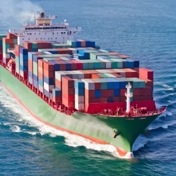 Grünes Containerschiff mit roten Containern und weißem Aufbau auf dem Wasser – Symbol für effiziente Schiffdieselmotoren und richtige Schmierung.