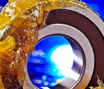 Kugellager mit Schmierfett überzogen vor blauem verschwommenem Hintergrund, Basis-Schmierstoffwissen für Praktiker