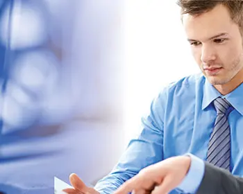 Two experts discussing documents; on the left, engine oil is being poured from a canister – symbolizing a seminar on the basics of lubrication.