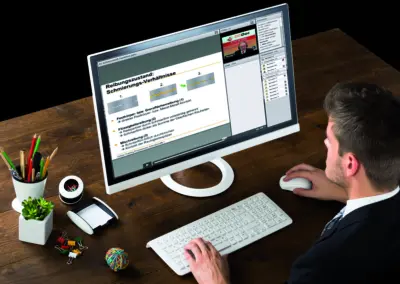 Businessman sitting at his desk participating in an OilDoc online training course on lubrication and friction conditions on a large monitor