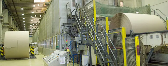 Production hall with large paper machine and wound paper roll in a paper factory