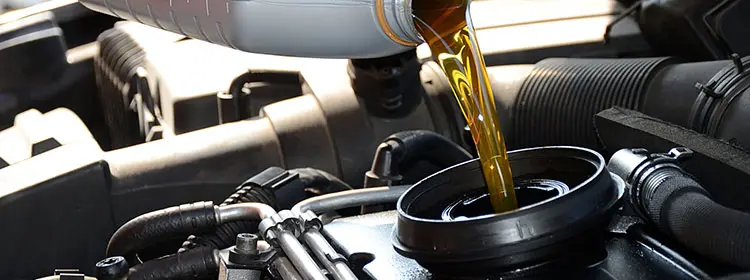Golden motor oil is poured from a canister into a car engine.
